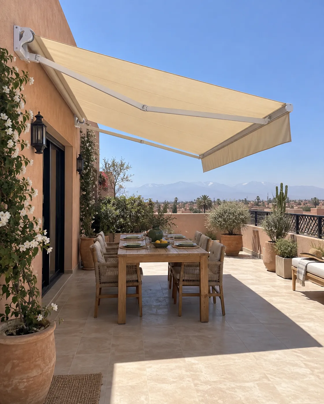 Store banne Marfil ouvert au-dessus d’une table sur une terrasse à Marrakech